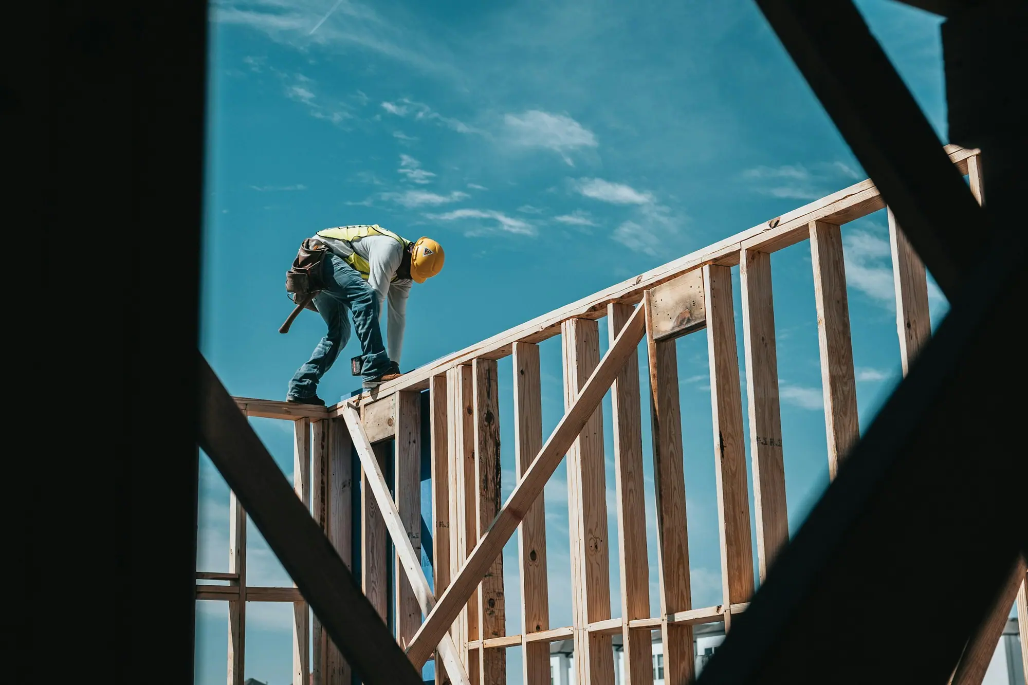 Framer in a hard hat working on the wall framing of a new house