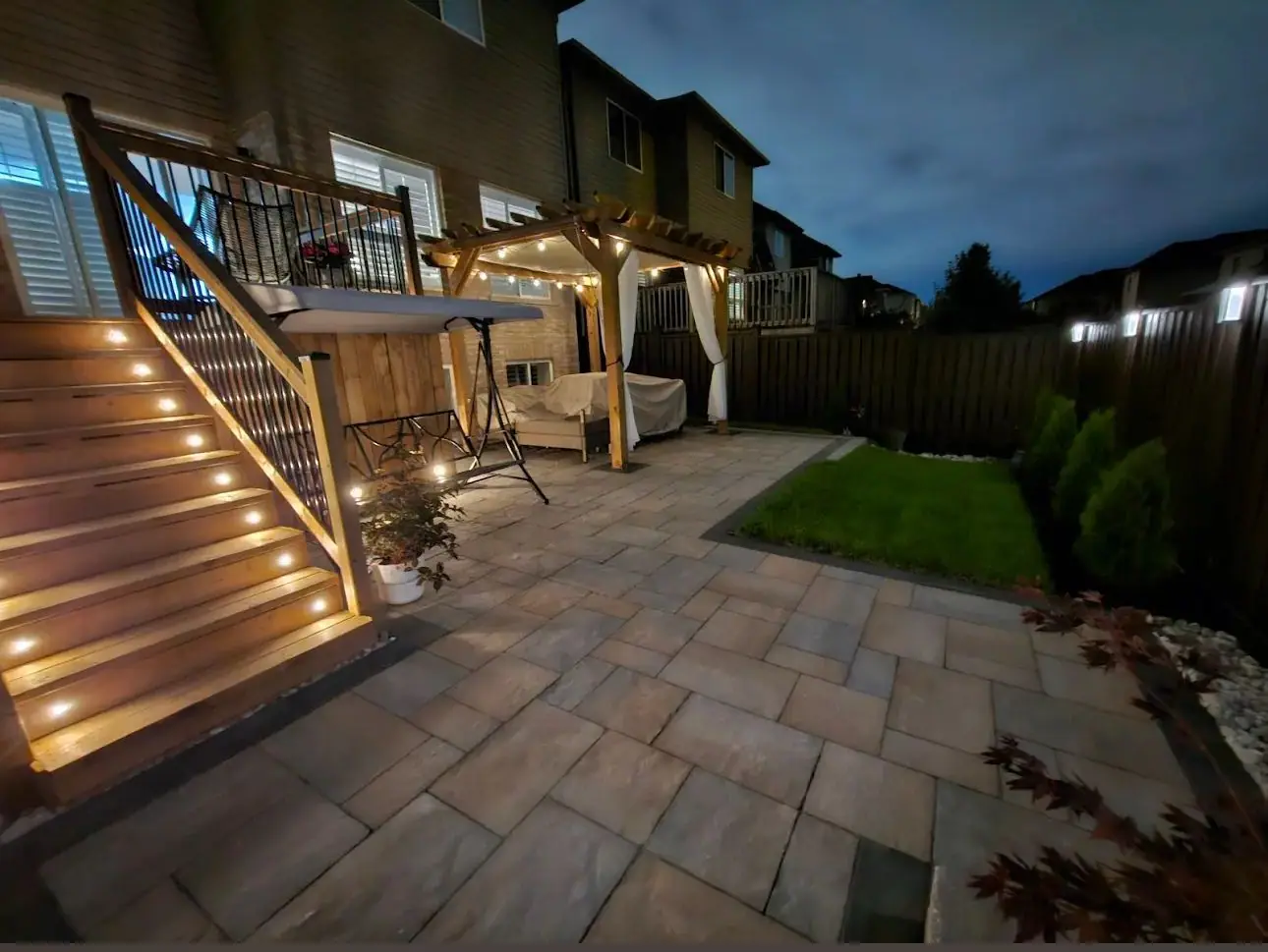 Deck stairs with step lighting and an interlock patio at dusk