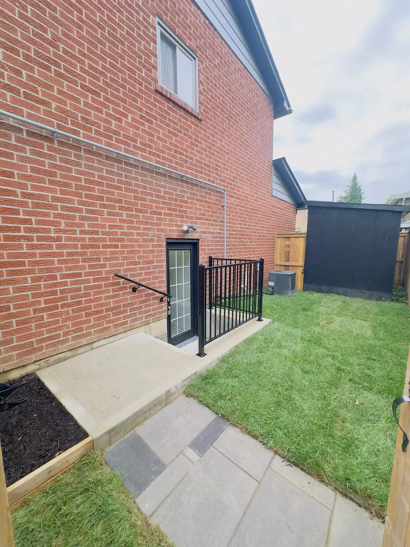 Concrete walkway to a below-grade side entrance with railing
