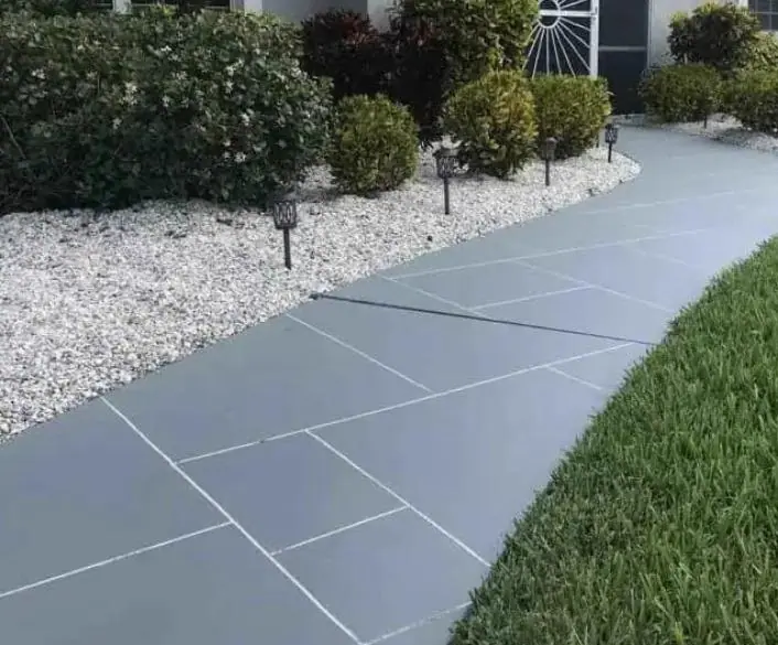 Grey concrete walkway with stone border and landscaping