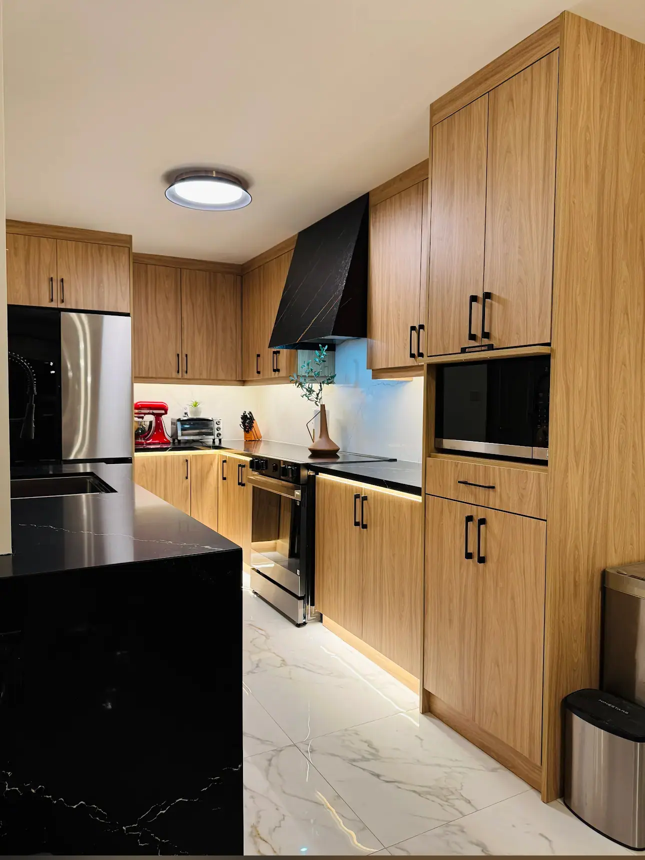 Kitchen with warm wood cabinets, black quartz and wall ovens