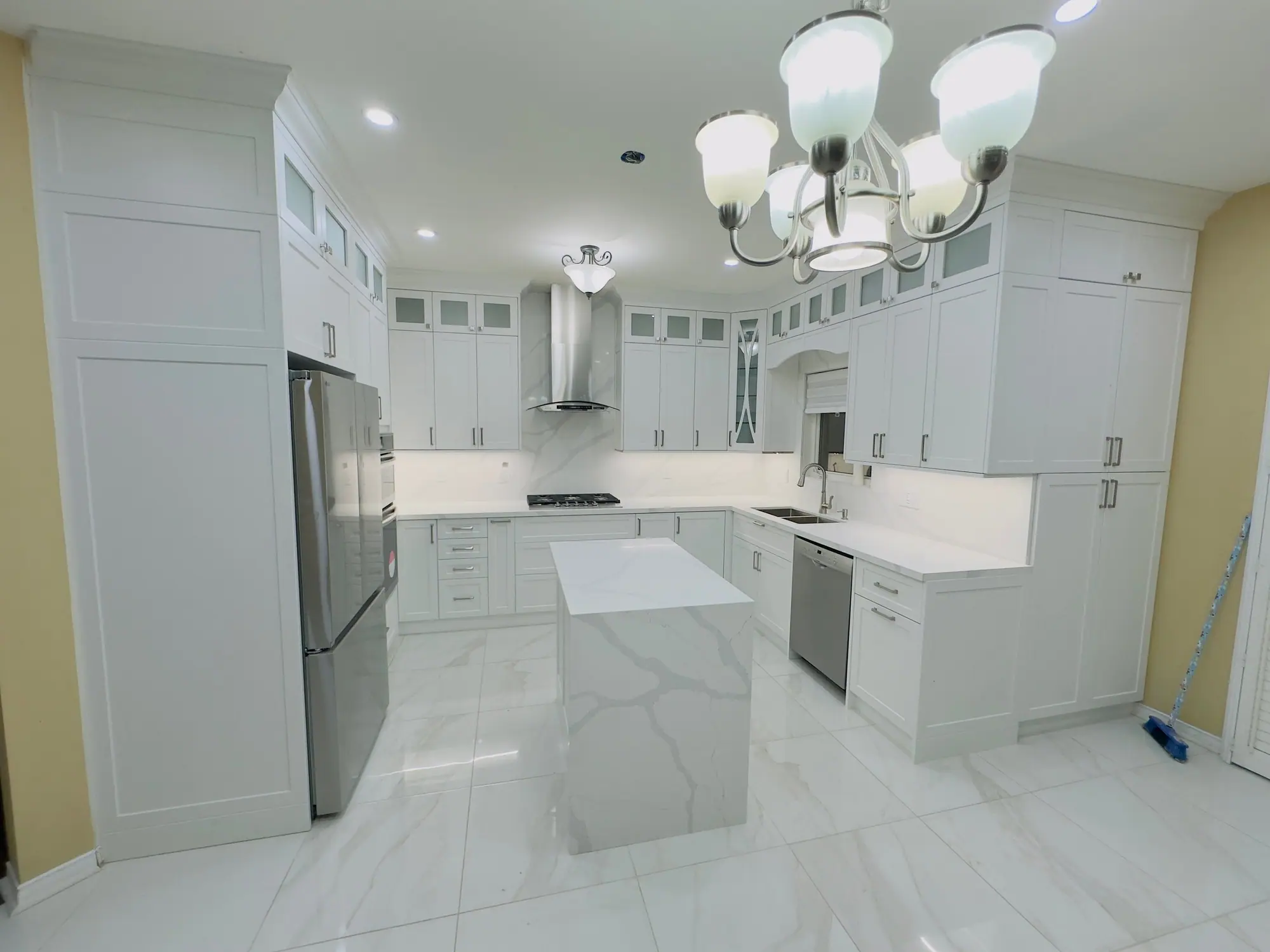 White shaker kitchen with marble-look porcelain floor and island