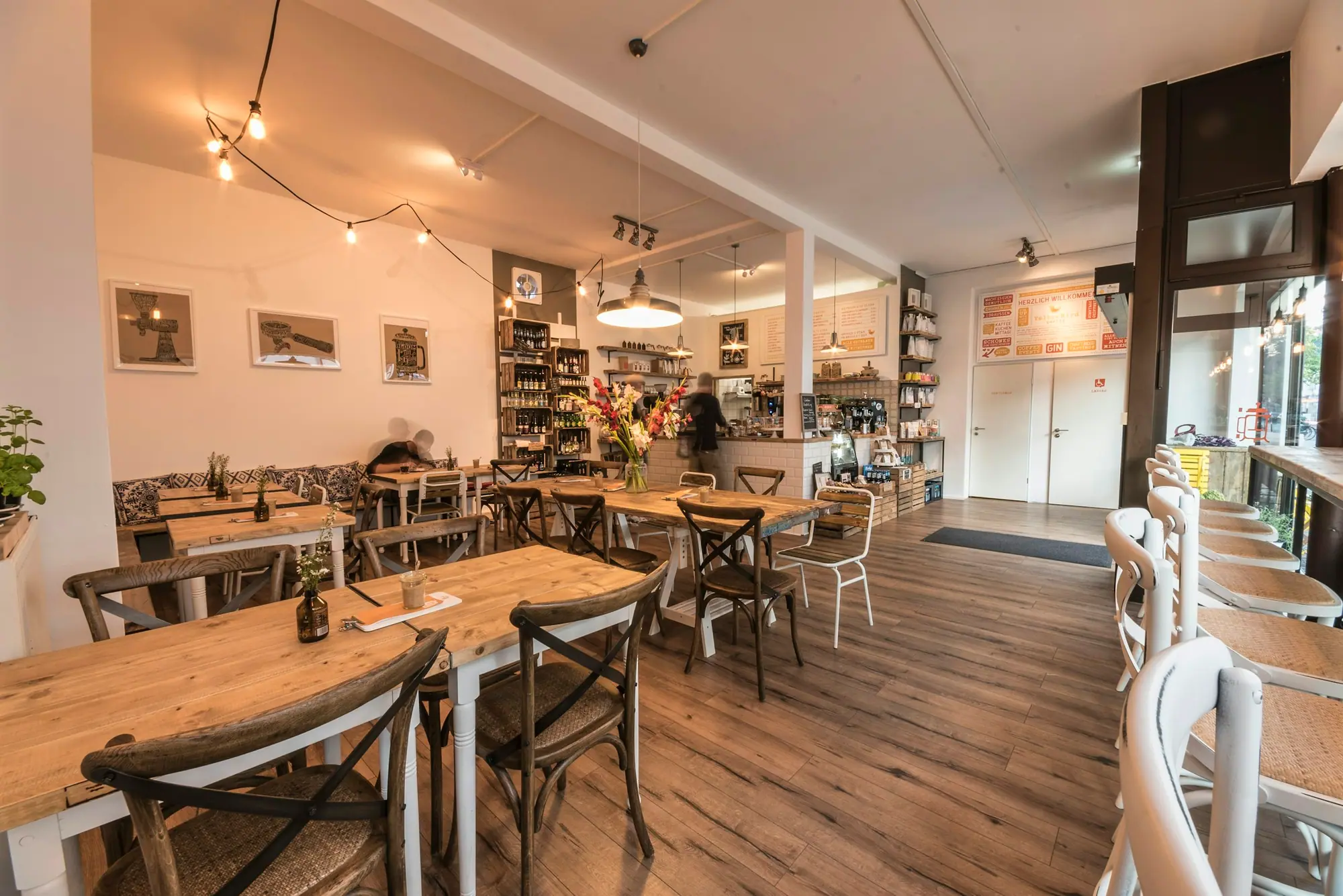 Bright café dining room with wood tables and white walls