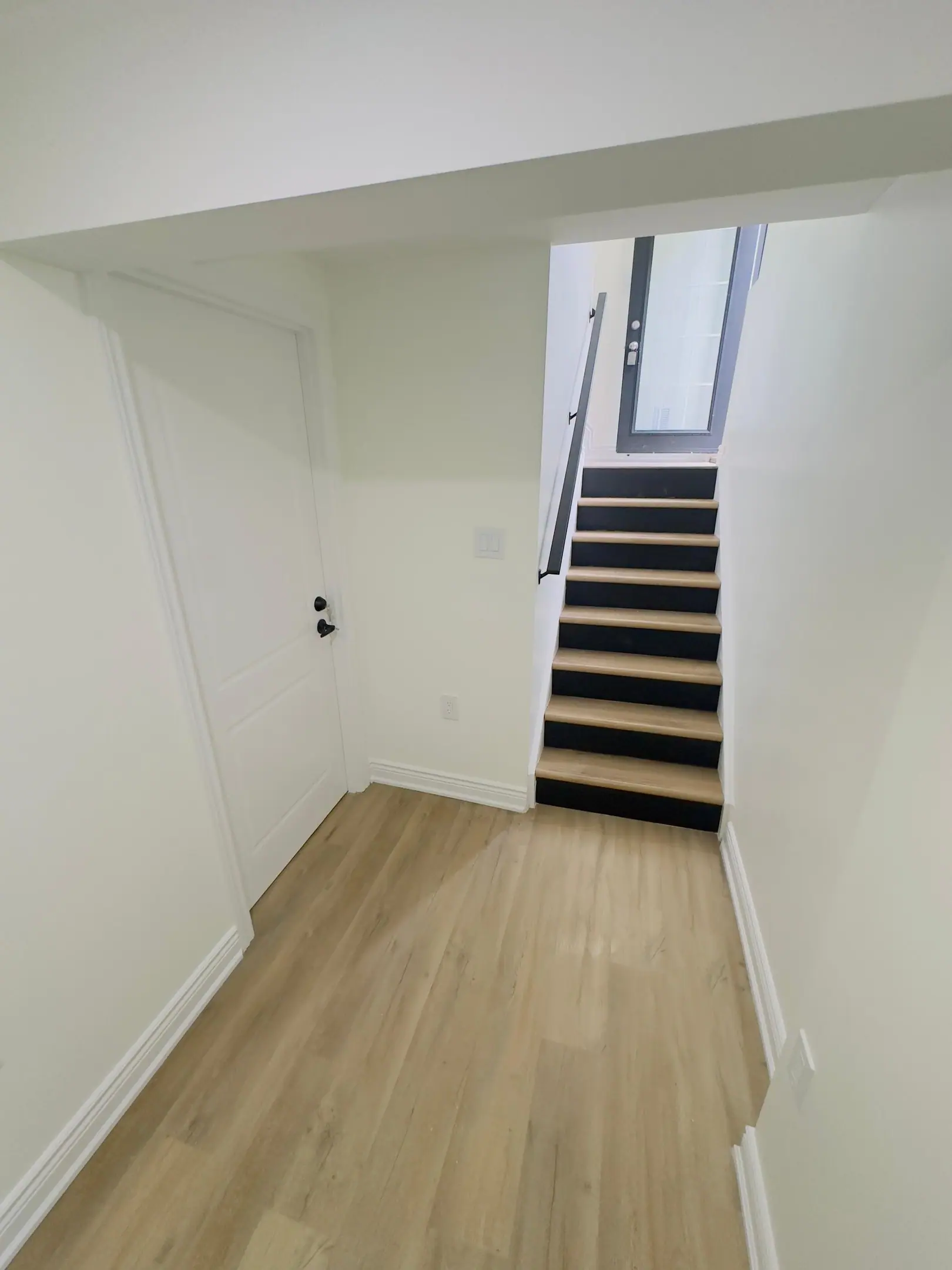 Basement stairs with dark treads and a new handrail