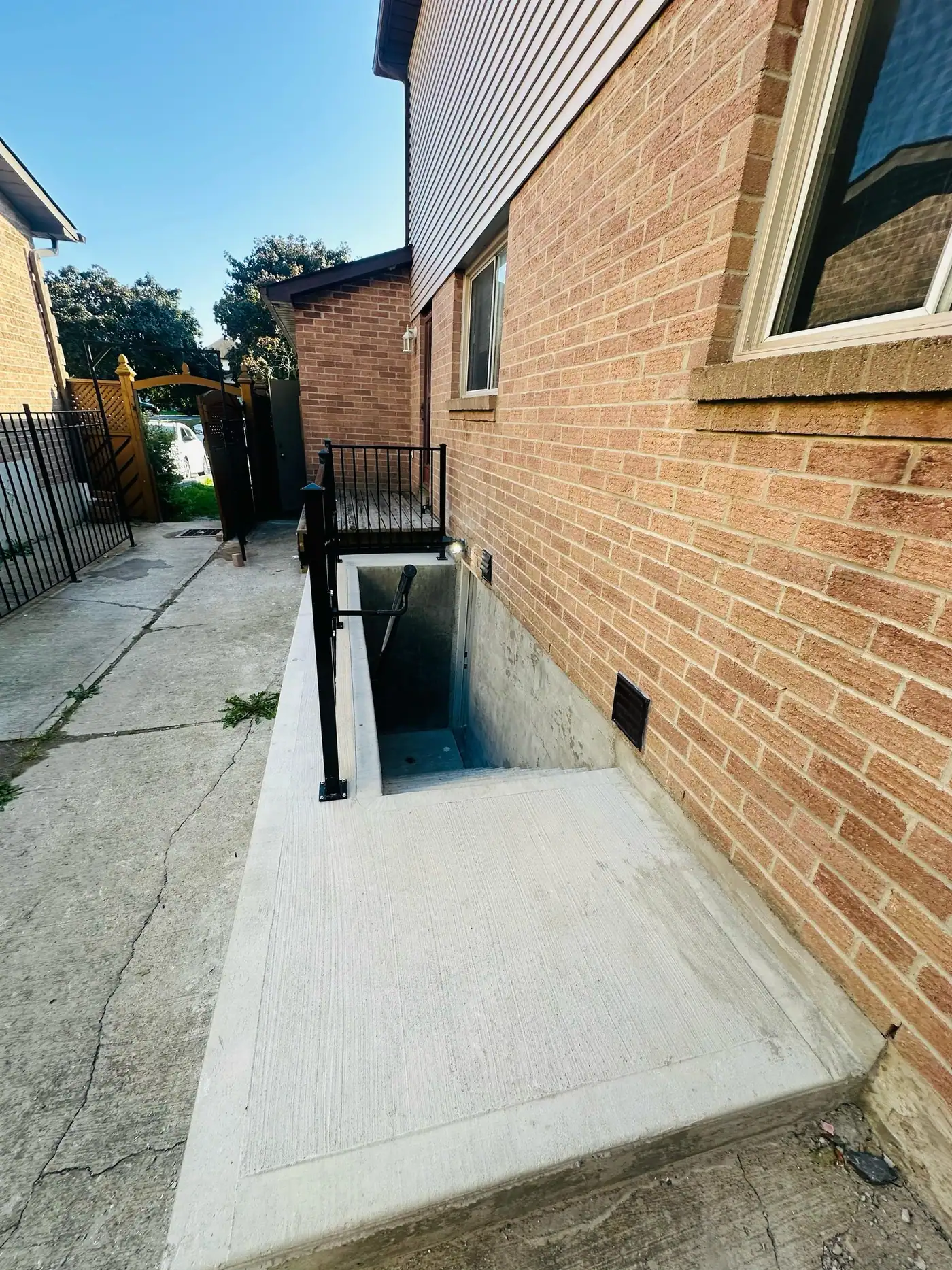 Below-grade side entrance with concrete stairs and railing