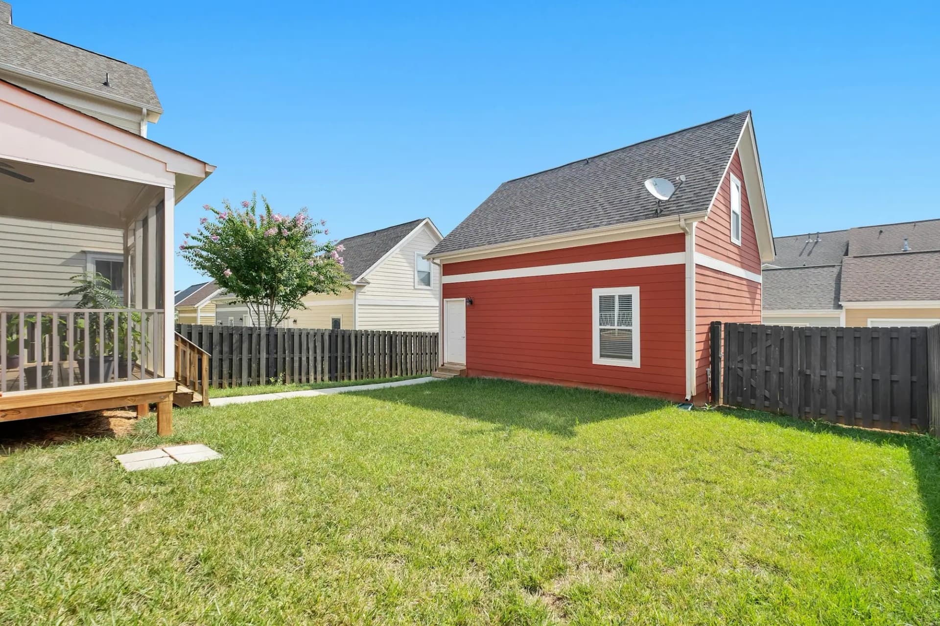 Detached backyard suite with red siding behind a house