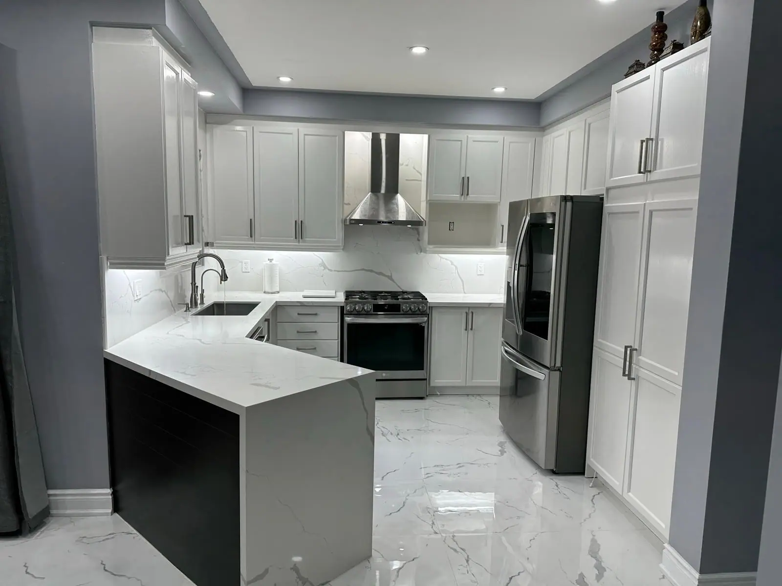 Grey kitchen with stainless range hood and black peninsula