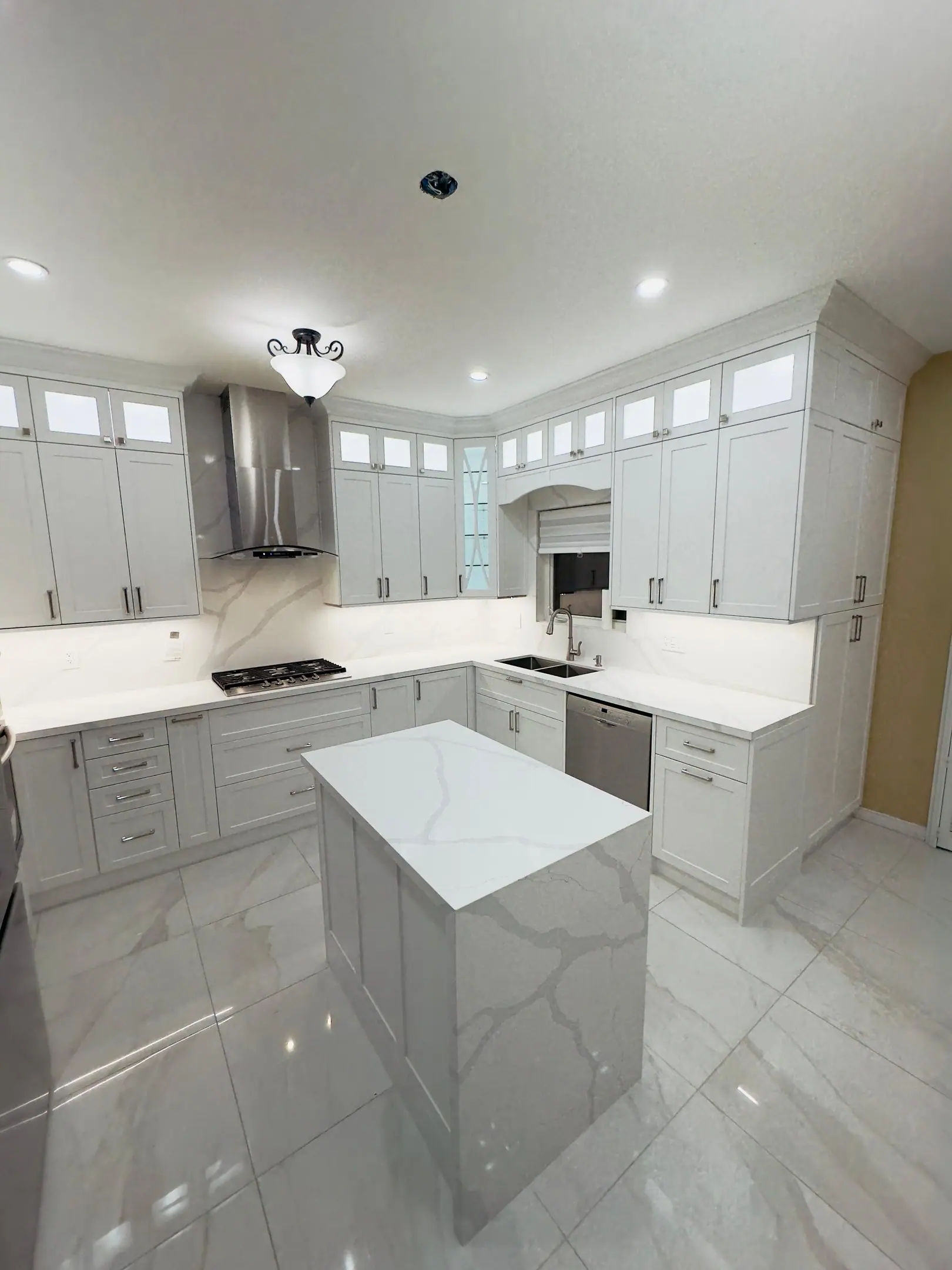 White kitchen with marble-look island and porcelain floor