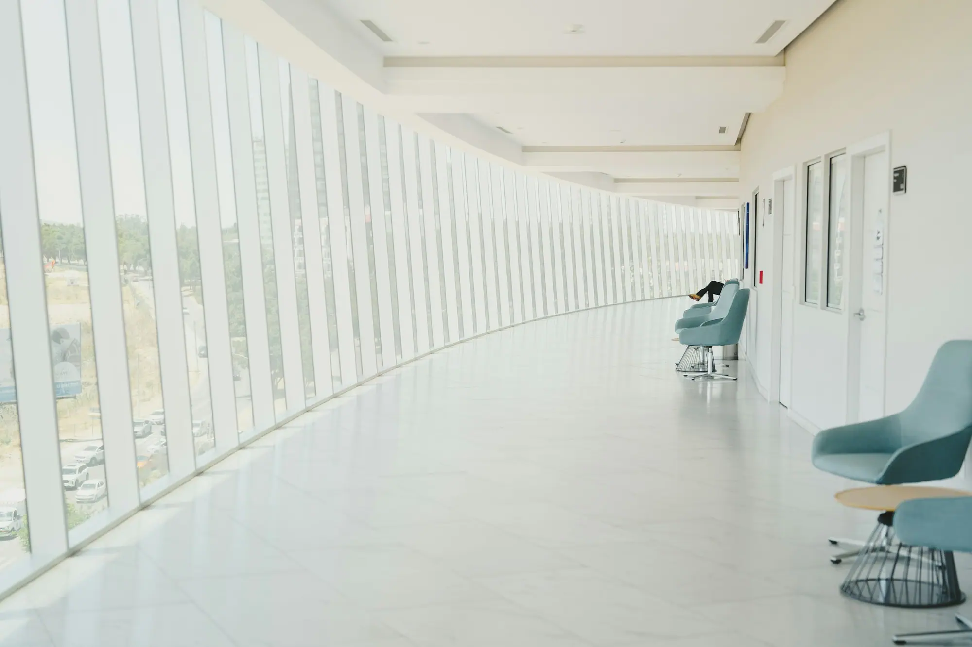 Bright clinic hallway with waiting chairs along the wall